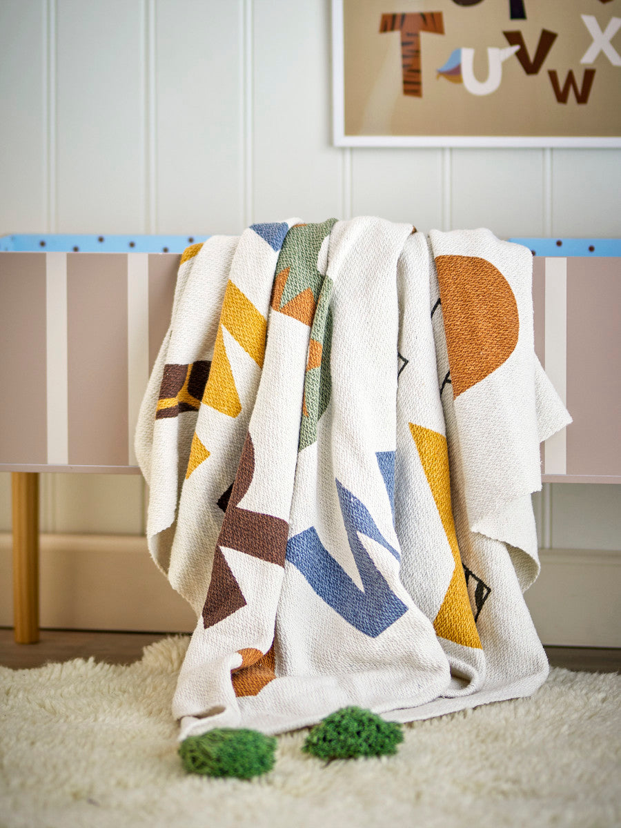 שמיכת כותנה צבעונית על ספסל בחדר ילדים
